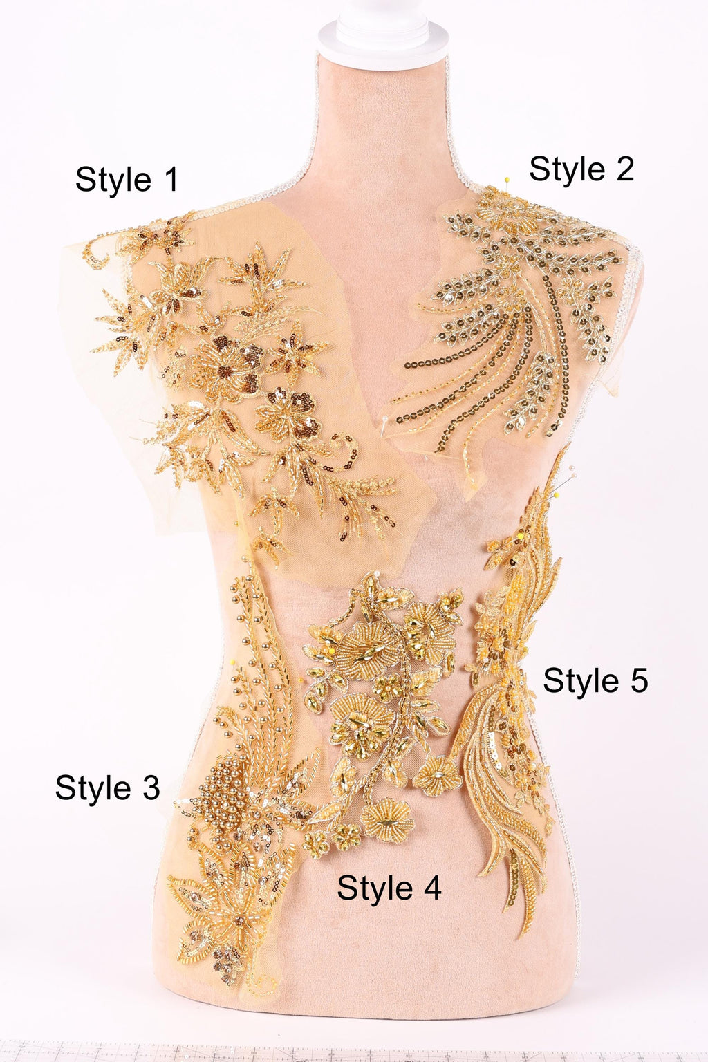 A mannequin with various gold and beige embroidered designs on its body, including floral patterns, leaves, and other decorative elements.
