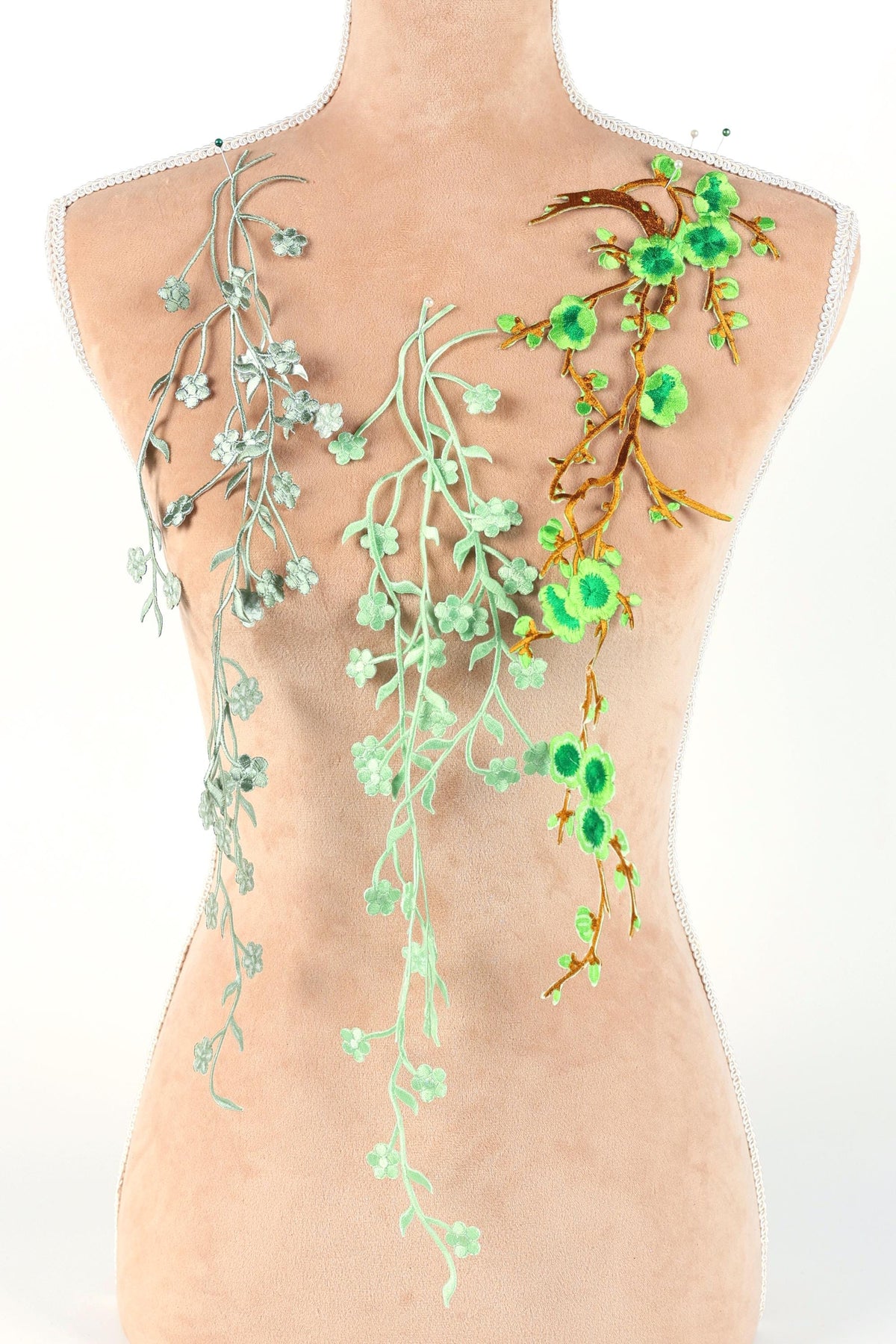 a mannequin torso adorned with a variety of green and white floral and leaf-like designs, creating a visually striking and nature-inspired appearance.