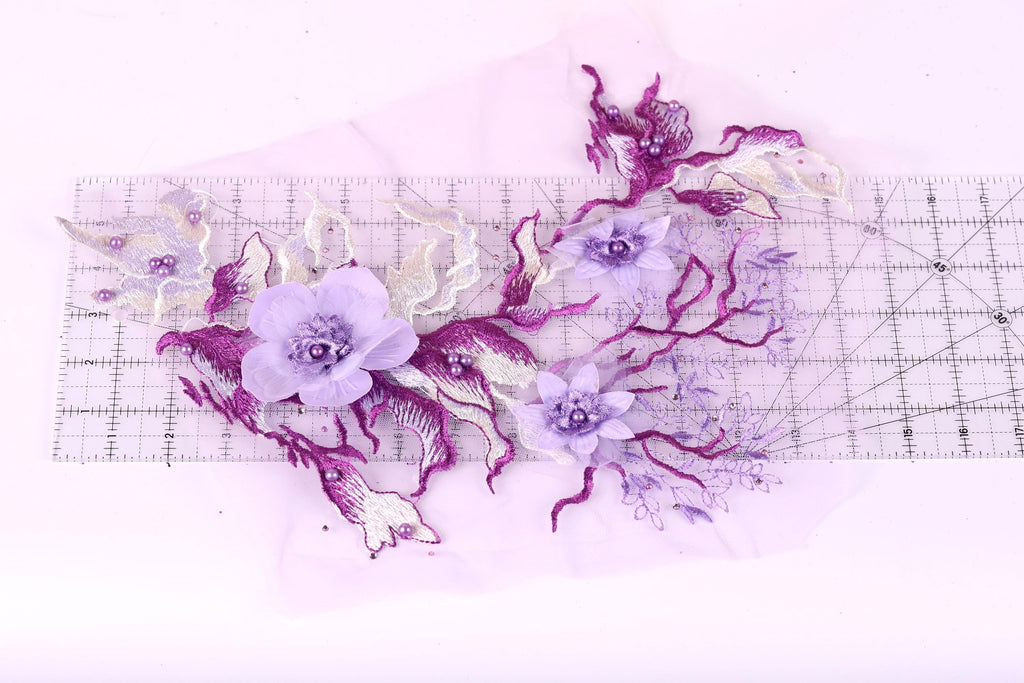 a close-up view of a delicate floral arrangement composed of purple and white flowers, with some purple flowers and leaves. The arrangement is placed on a transparent surface, allowing the viewer to see the intricate details of the flowers and leaves.