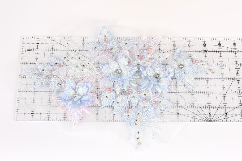 a collection of delicate, intricately designed blue and white flowers and leaves, arranged on a transparent ruler.