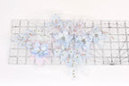 a collection of delicate, intricately designed blue and white flowers and leaves, arranged on a transparent ruler.