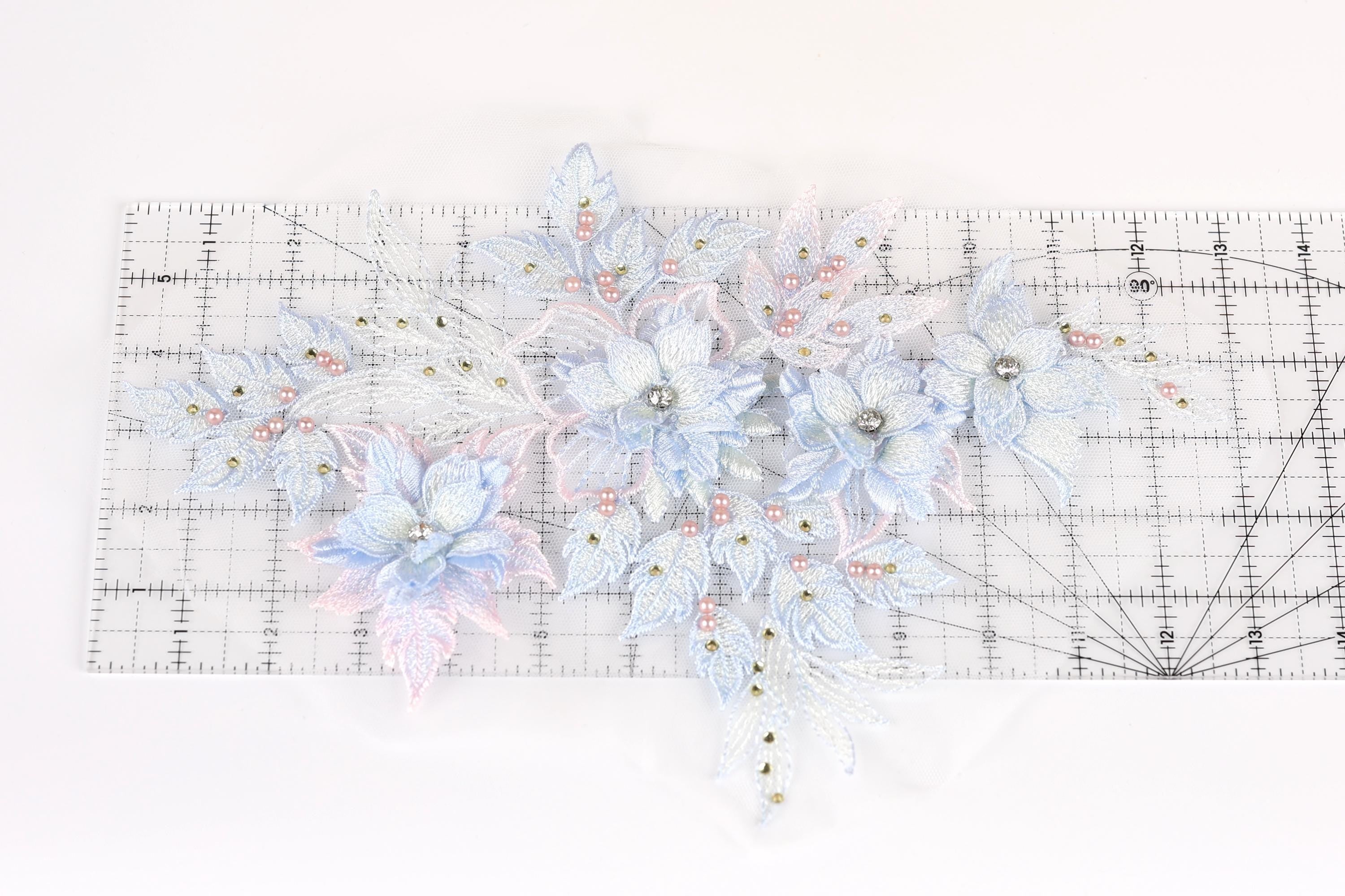 a collection of delicate, intricately designed blue and white flowers and leaves, arranged on a transparent ruler.