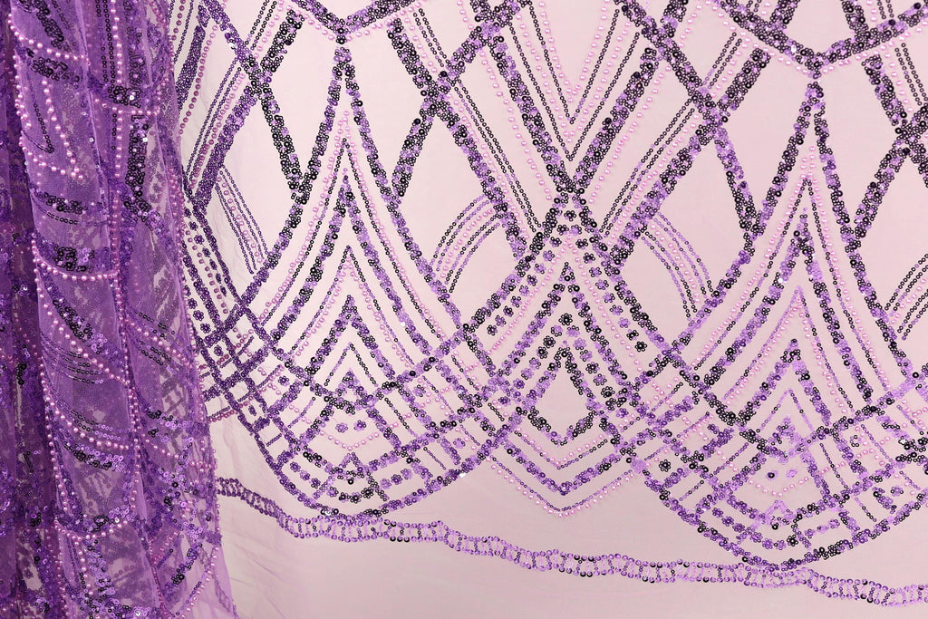 a close-up view of a fabric with a purple and black sequin pattern. The fabric appears to be a sheer material, with a repeating pattern of diamond shapes and lines in shades of purple and black. The pattern is intricate and visually striking, with the sequins adding a touch of sparkle and texture to the overall design.