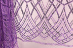 a close-up view of a fabric with a purple and black sequin pattern. The fabric appears to be a sheer material, with a repeating pattern of diamond shapes and lines in shades of purple and black. The pattern is intricate and visually striking, with the sequins adding a touch of sparkle and texture to the overall design.