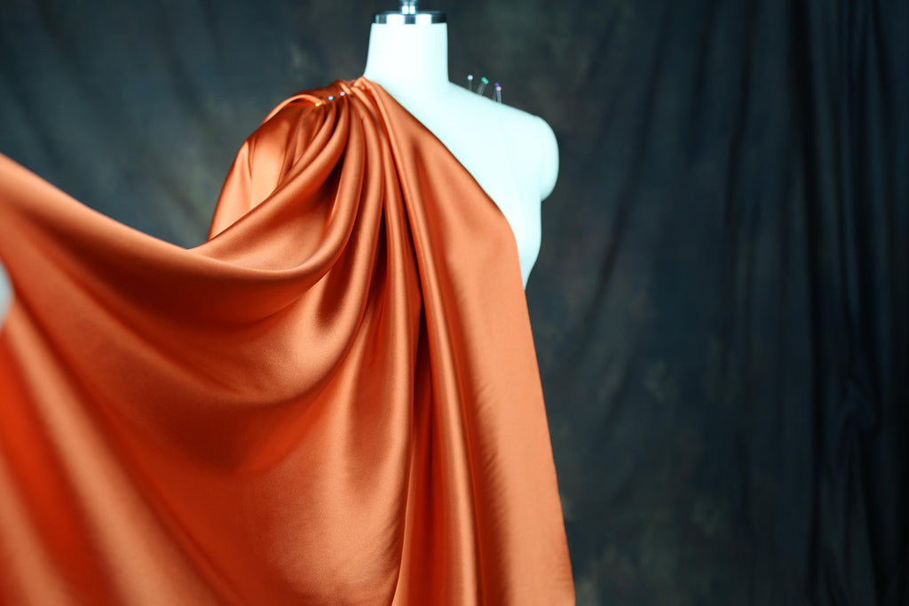 a mannequin wearing an orange draped dress