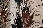 The image is a close-up of a fabric with a floral pattern, featuring a mix of black, brown, and white sequins and beads. The pattern is intricate and detailed, with the sequins and beads arranged in a way that creates a visually striking design.