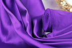 a close-up view of a purple fabric, possibly silk or satin, with a rolled-up end visible.