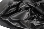 a close-up view of a crumpled, shiny black fabric, possibly silk or satin, with a textured and wrinkled appearance.