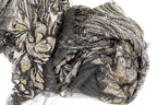 a close-up view of a fabric with a black and gold pattern, featuring a mix of sequins and lace-like elements. The fabric appears to be a sheer material, with a black and gold color scheme.