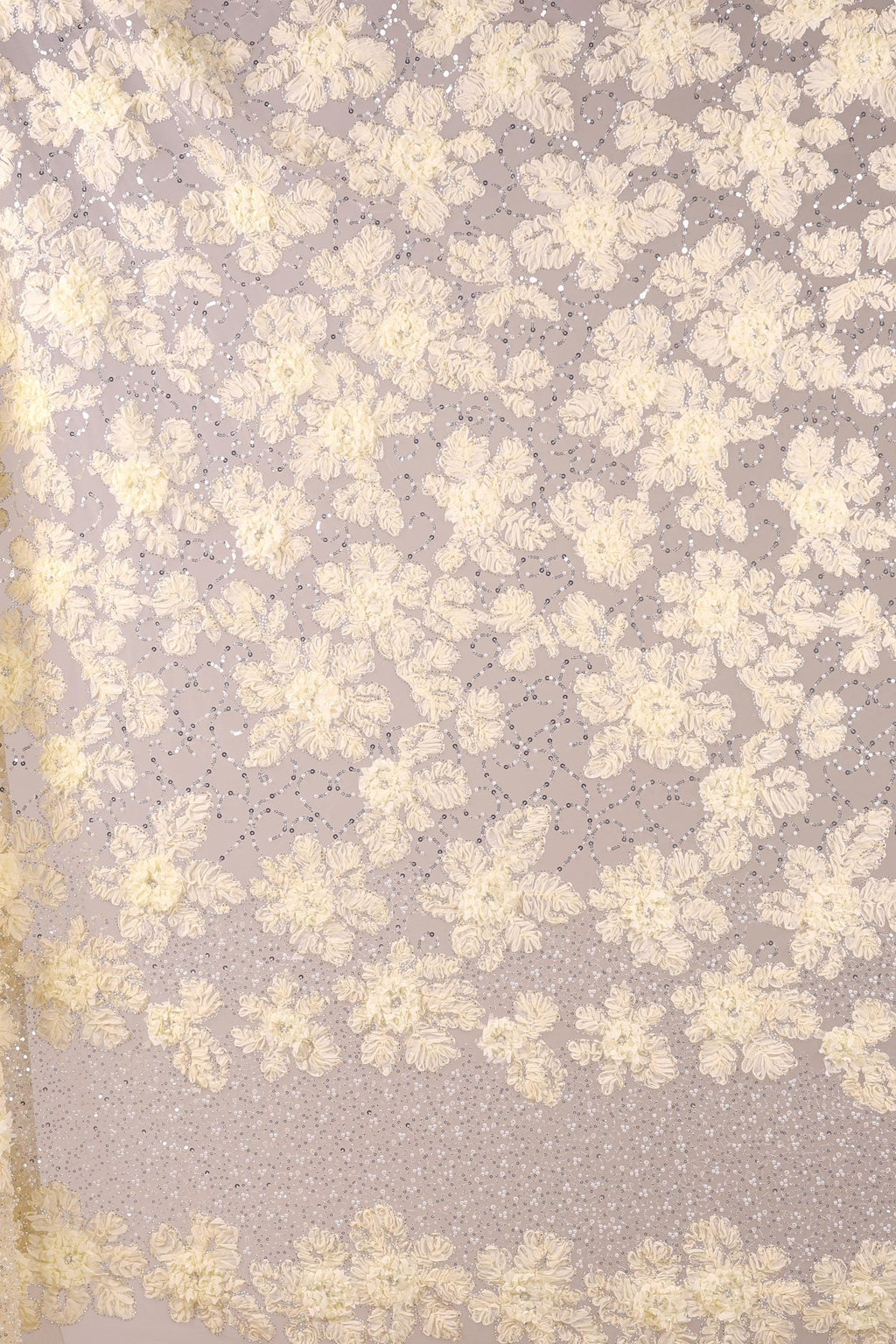 a close-up view of a fabric with a floral pattern, consisting of numerous small white flowers arranged in a repeating pattern. The fabric appears to be made of a sheer material, giving it a delicate and airy appearance. The image does not contain any text or other discernible objects, and the focus is solely on the floral pattern on the fabric.