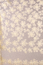 a close-up view of a fabric with a floral pattern, consisting of numerous small white flowers arranged in a repeating pattern. The fabric appears to be made of a sheer material, giving it a delicate and airy appearance. The image does not contain any text or other discernible objects, and the focus is solely on the floral pattern on the fabric.