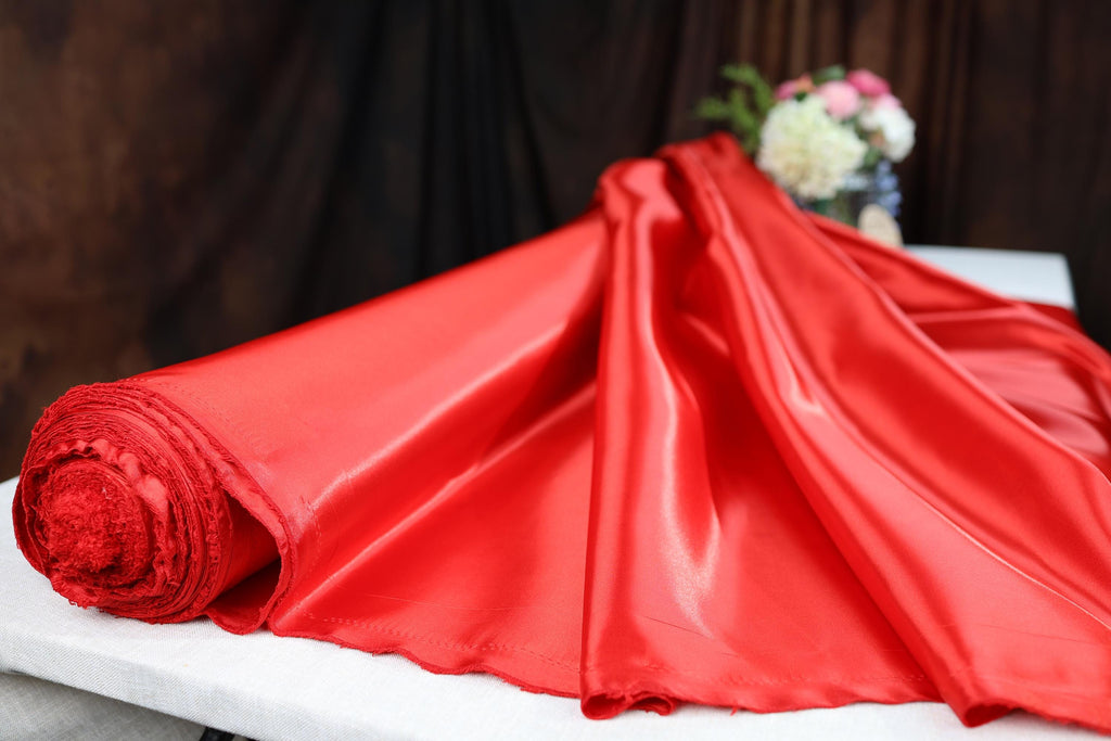 a red cloth on a table with a vase of flowers in the background