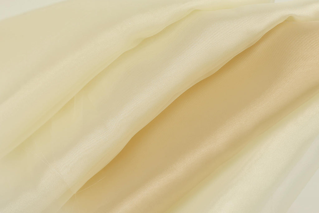 The image is a close-up of a fabric with a soft, flowing texture in shades of yellow and cream.