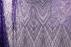 a close-up view of a fabric with a purple and white pattern, consisting of a repeating diamond-shaped motif with a metallic sheen. The pattern is composed of numerous small dots and lines, creating a visually striking and intricate design.