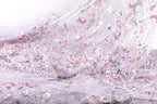 a close-up view of a delicate, intricately embroidered fabric with a floral pattern. The fabric appears to be made of sheer material, giving it a soft and delicate appearance. The embroidery features a variety of colors and patterns, creating a visually appealing and detailed design.