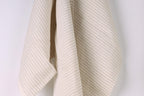 A beige and white striped fabric is hanging against a white wall.
