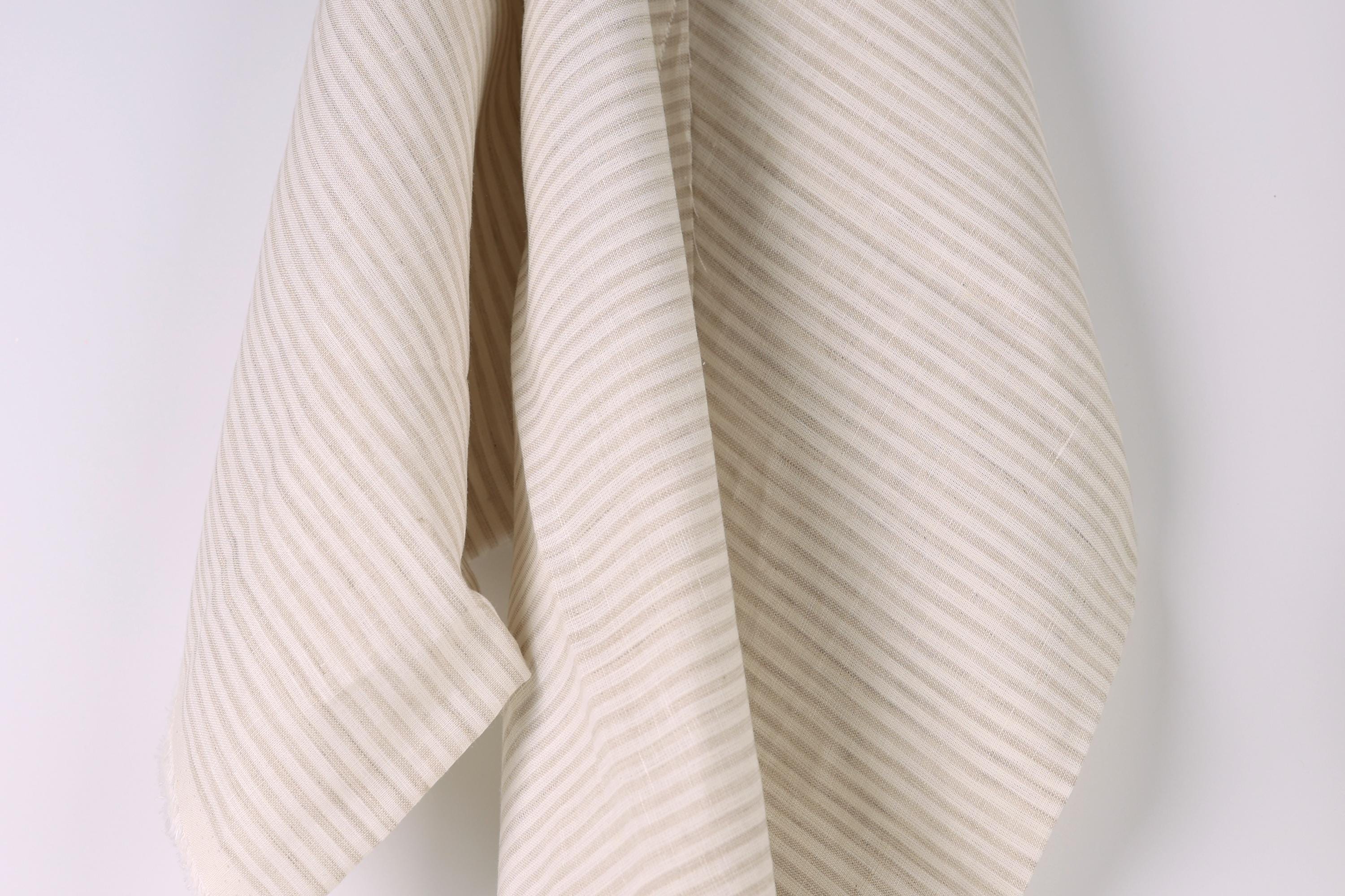 A beige and white striped fabric is hanging against a white wall.