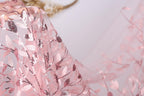 A close-up view of a delicate, pink lace fabric with a floral pattern.