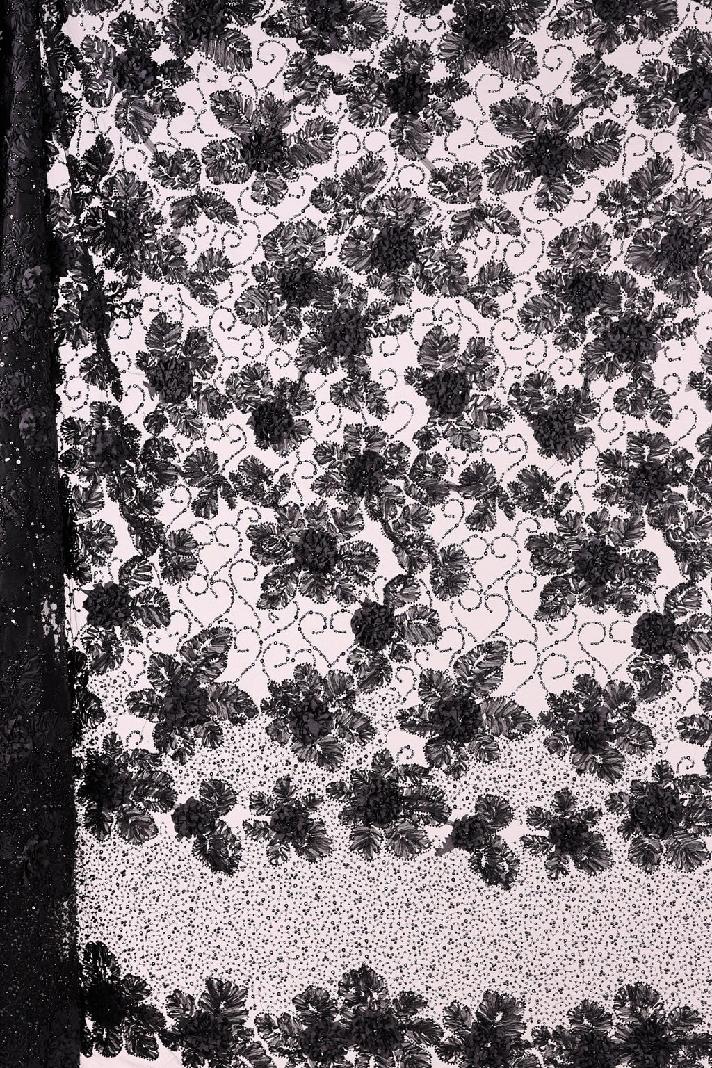The image is a close-up of a black and white fabric with a floral pattern. The fabric appears to be made of lace or a similar material, with a repeating floral design in black and white. The image does not contain any text or additional objects, and the focus is solely on the intricate floral pattern on the fabric.
