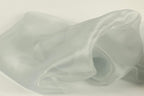The image is a close-up of a soft, flowing fabric, possibly silk or chiffon, with a light gray or pale green color. The fabric appears to be wrinkled and has a smooth texture, giving it a delicate and elegant appearance.