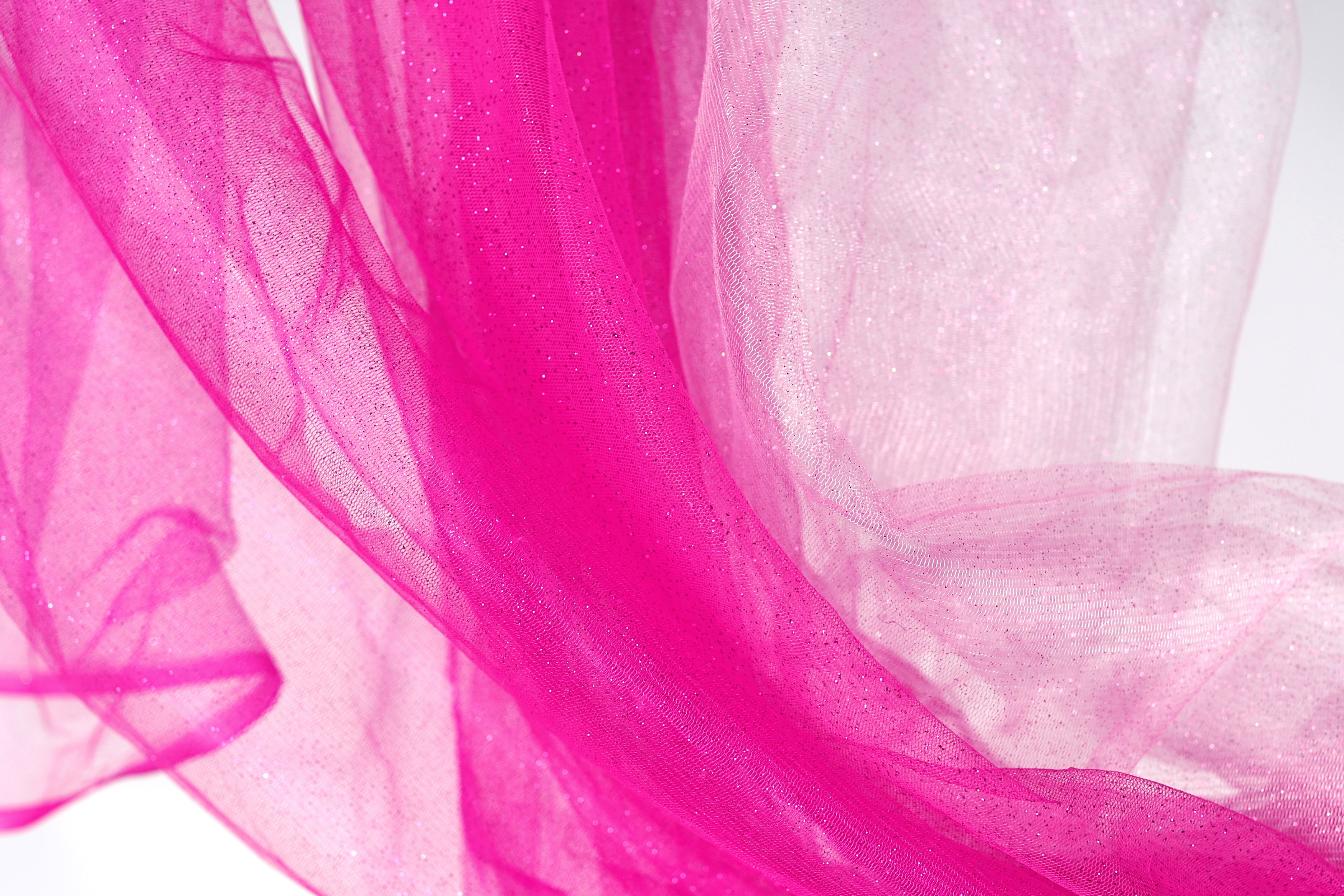a close-up view of a pink and white fabric, with the pink fabric appearing more vibrant and the white fabric appearing more subdued.