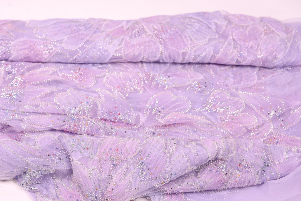 a close-up view of a fabric with a purple floral pattern, featuring small white and silver embellishments.