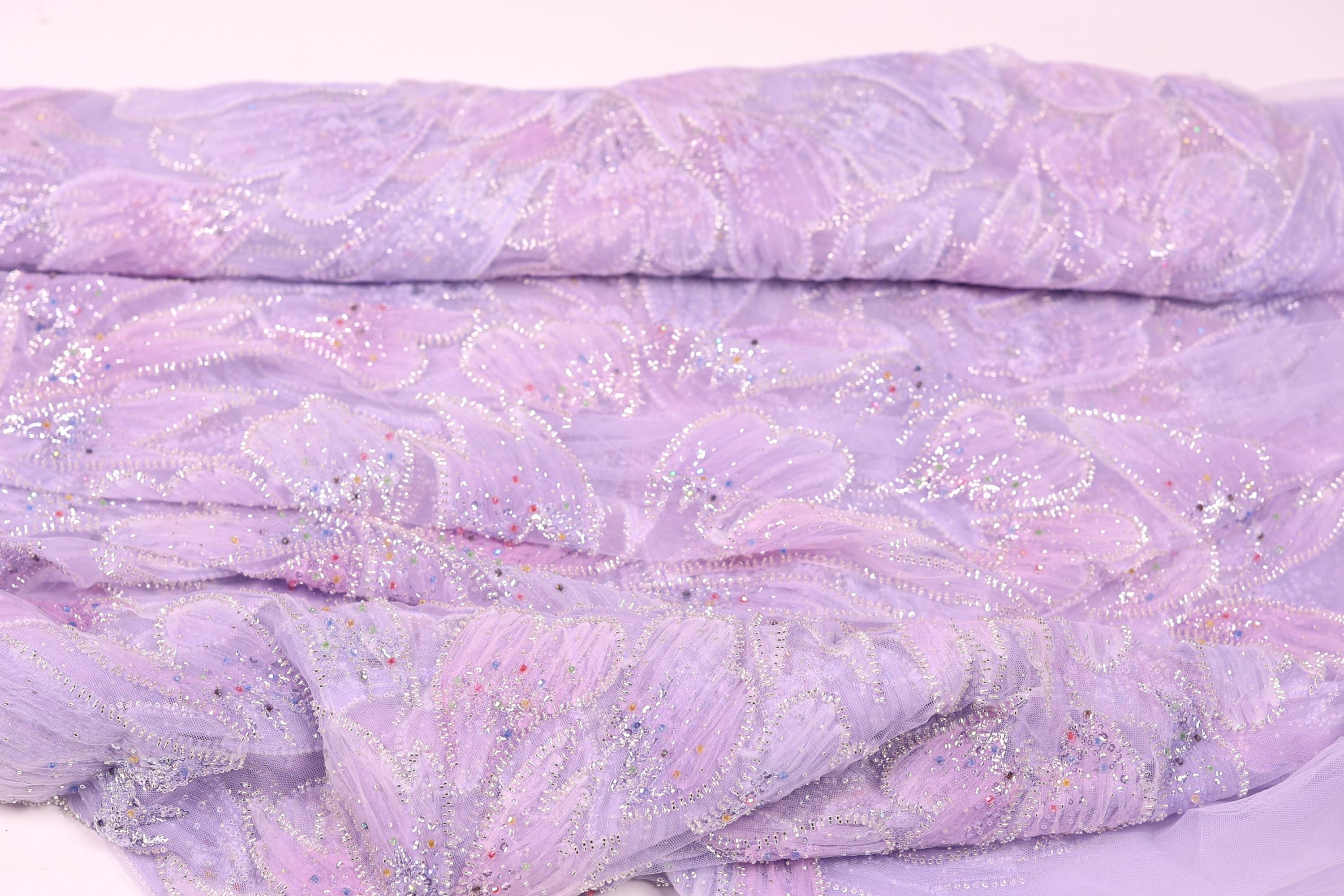 a close-up view of a fabric with a purple floral pattern, featuring small white and silver embellishments.