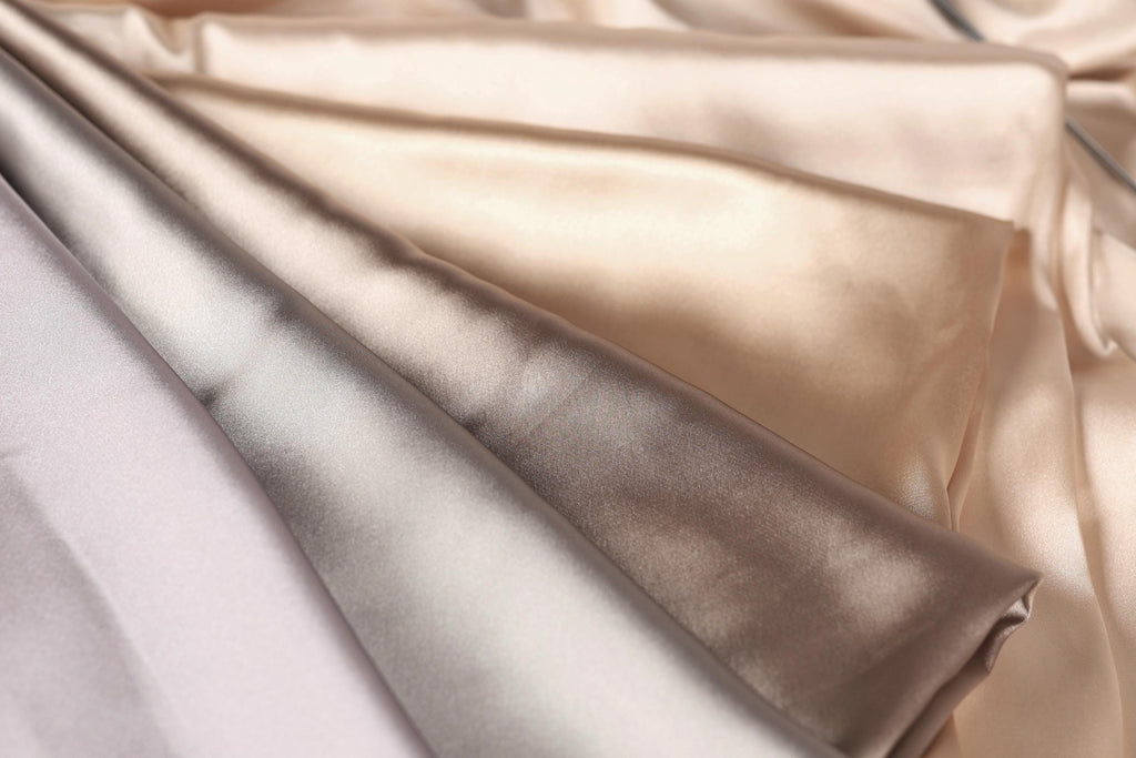 a close-up view of a fabric with a variety of colors, including shades of brown, beige, and gray. The fabric appears to be folded or crumpled, creating a visually interesting texture.