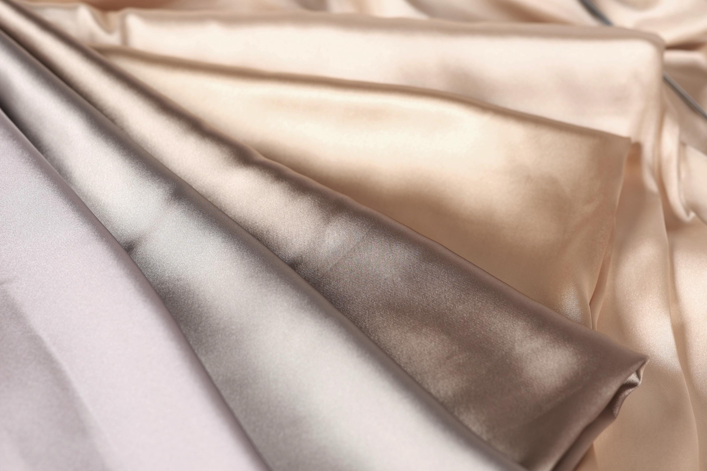 a close-up view of a fabric with a variety of colors, including shades of brown, beige, and gray. The fabric appears to be folded or crumpled, creating a visually interesting texture.