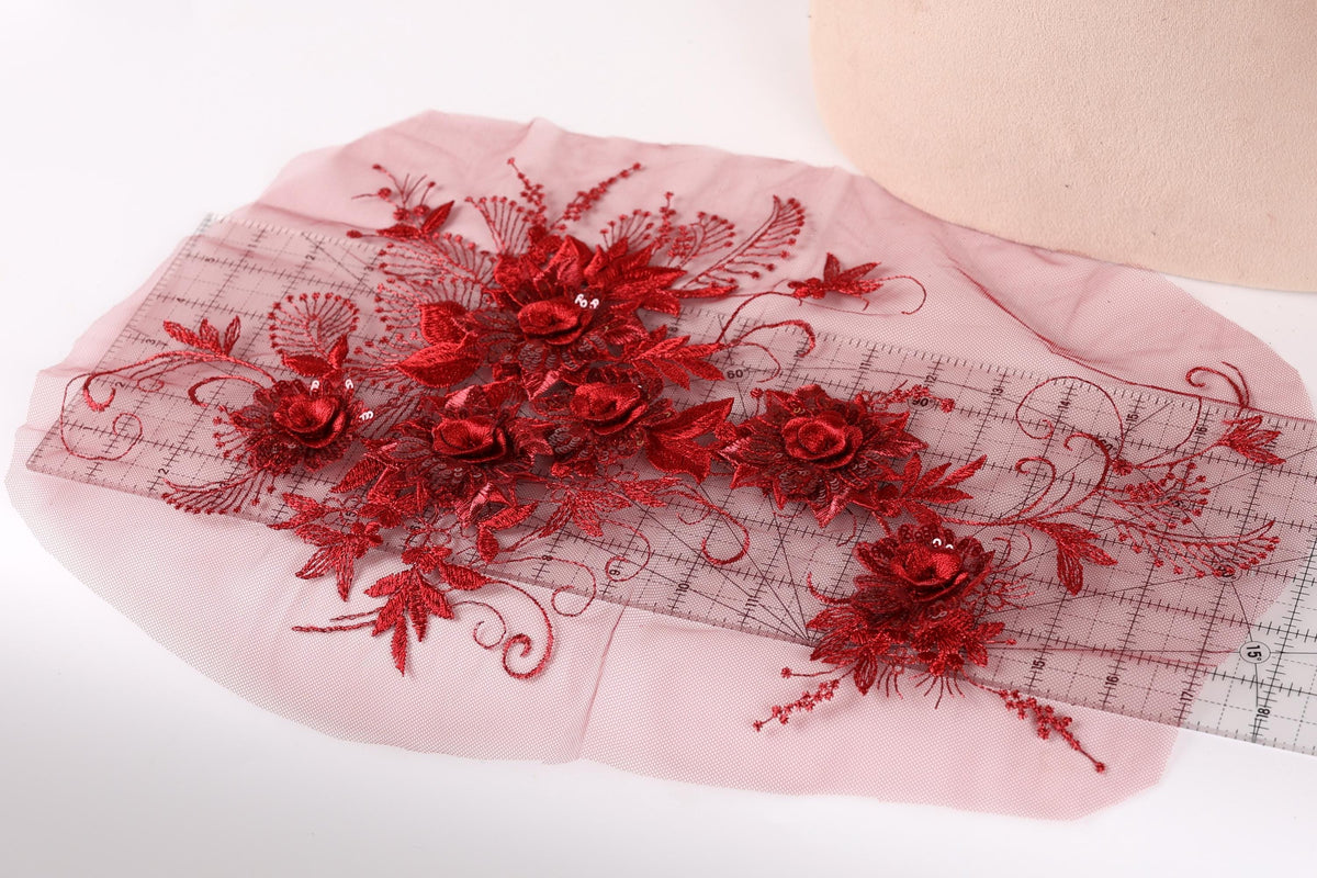 a pink fabric with red floral embroidery and a ruler placed on it.