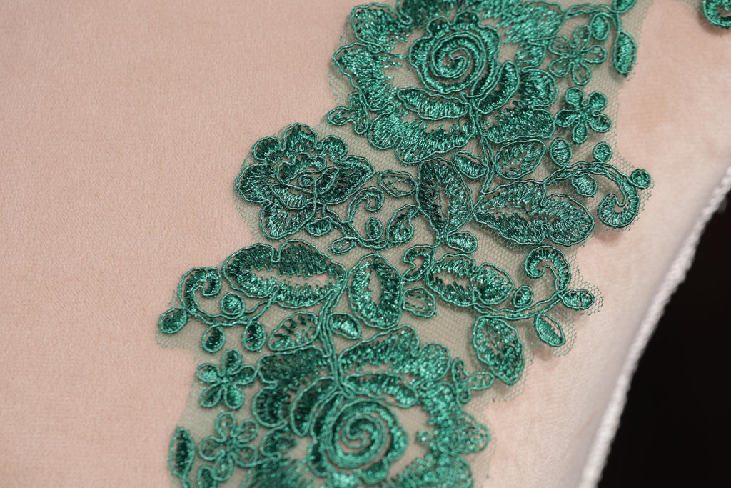 a close-up view of a delicate, intricate green lace pattern on a fabric surface.