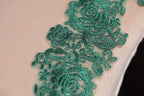 a close-up view of a delicate, intricate green lace pattern on a fabric surface.