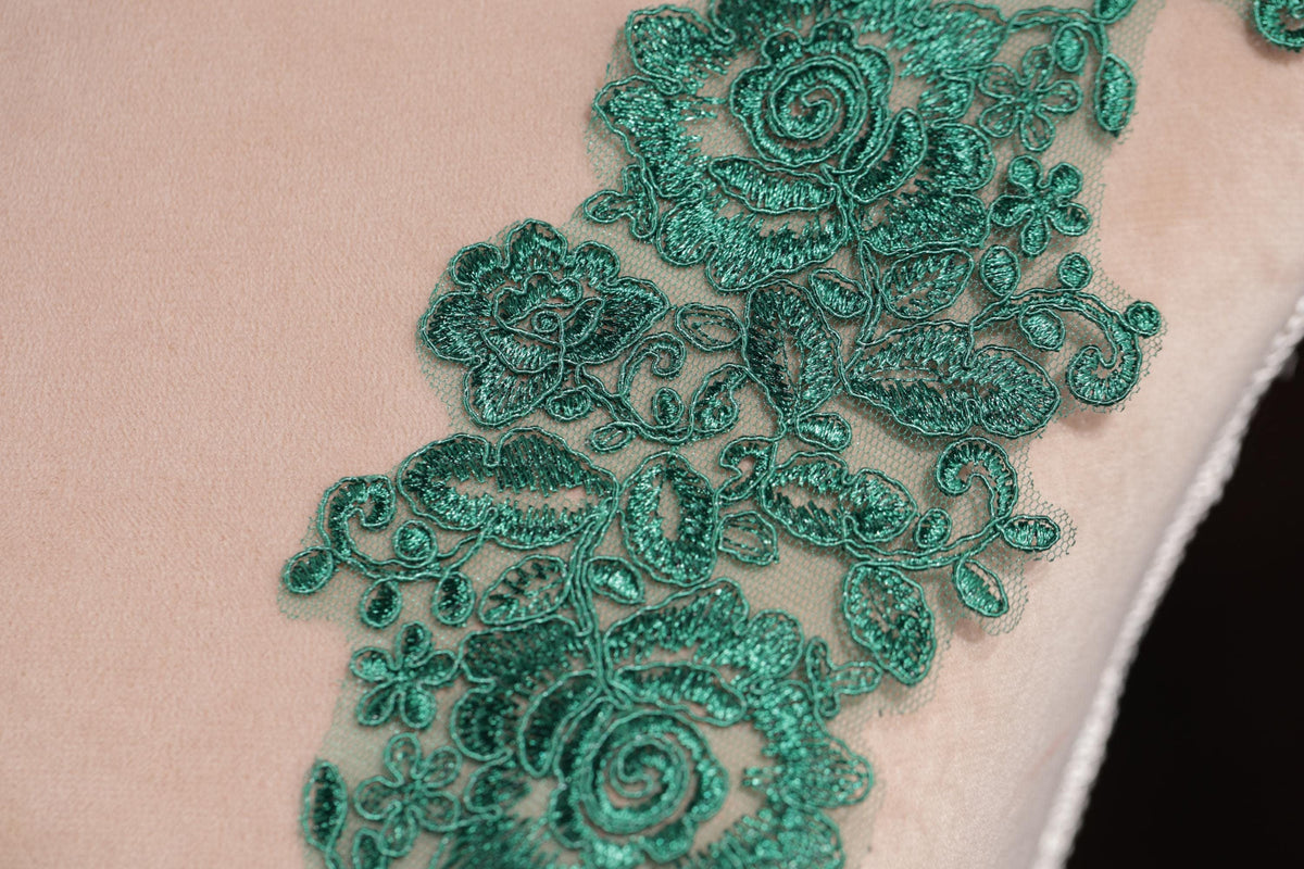 a close-up view of a delicate, intricate green lace pattern on a fabric surface.