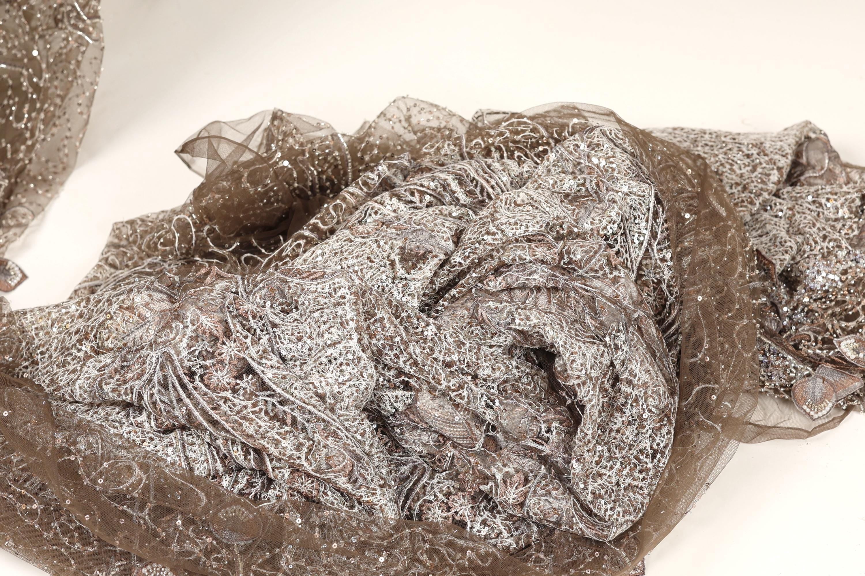 a close-up view of a piece of fabric with a brown and silver pattern, possibly a lace or chiffon material.