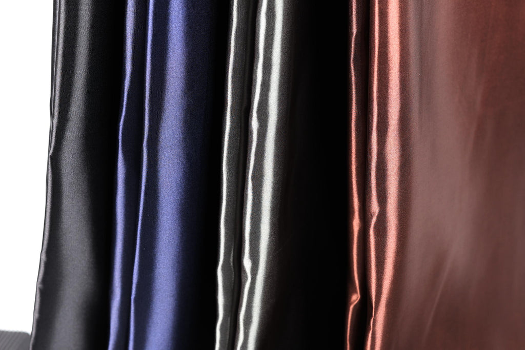 a close-up view of a collection of colorful satin fabric, with a focus on the vertical arrangement of the fabric.