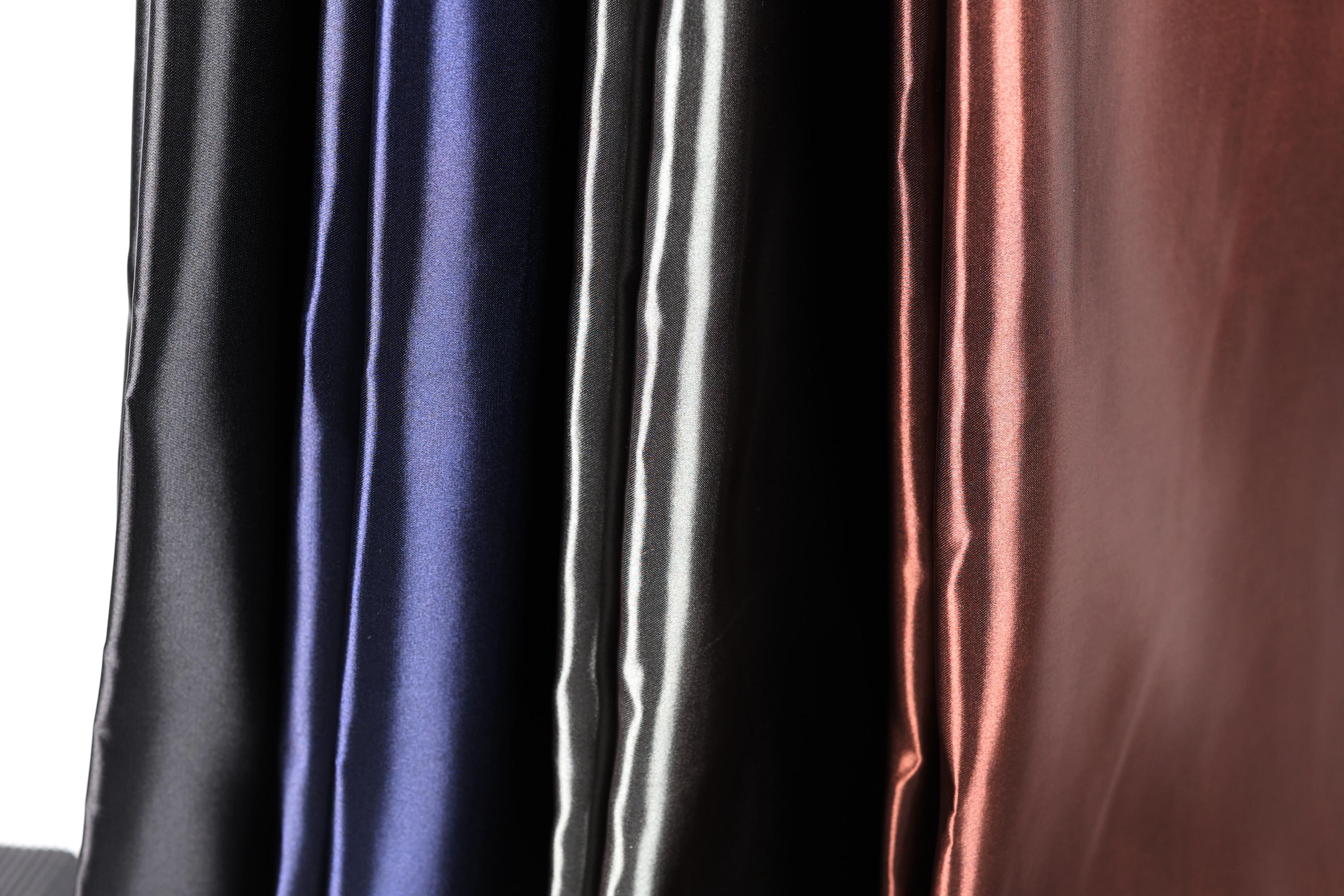 a close-up view of a collection of colorful satin fabric, with a focus on the vertical arrangement of the fabric.