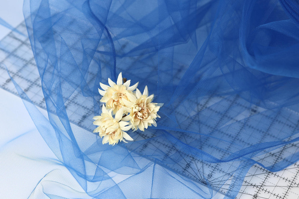 a close-up view of a delicate white flower resting on a blue fabric surface.