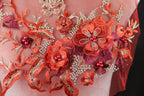 a close-up view of a delicate, intricately embroidered fabric with a floral design. The fabric is adorned with a variety of red flowers and leaves, as well as small red berries, creating a vibrant and eye-catching pattern. The embroidery work is detailed and precise, showcasing the skill and craftsmanship involved in creating this beautiful textile art piece.