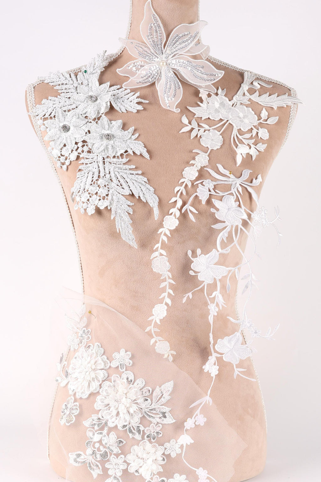 A mannequin wearing a white dress with intricate floral embroidery and lace details.