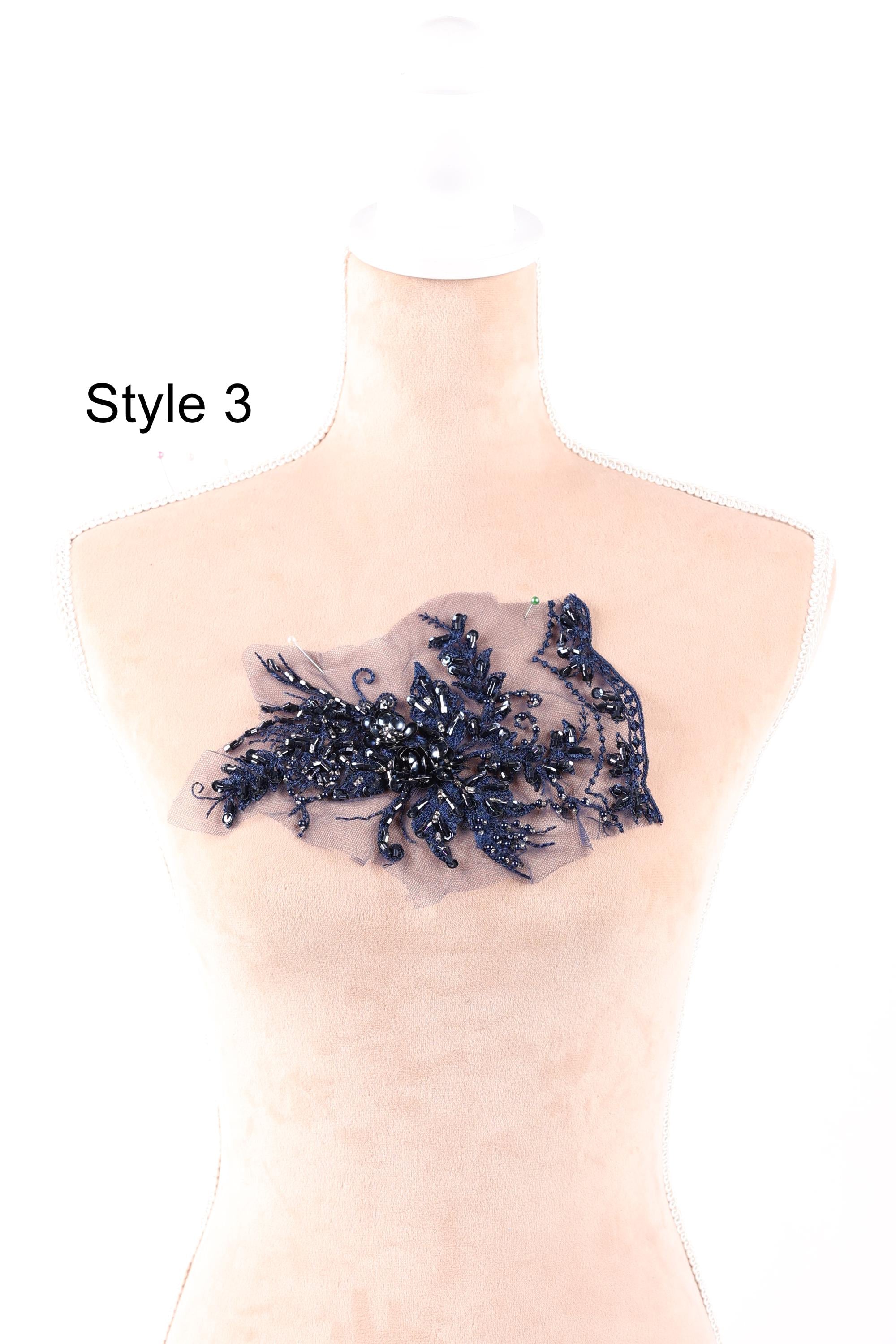 A mannequin wearing a dress with a decorative blue lace or beaded embellishment on the chest area.