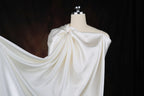 A mannequin wearing a white satin dress with a draped, flowing skirt.