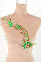 A mannequin torso with a decorative green leaf and branch embroidered on it.