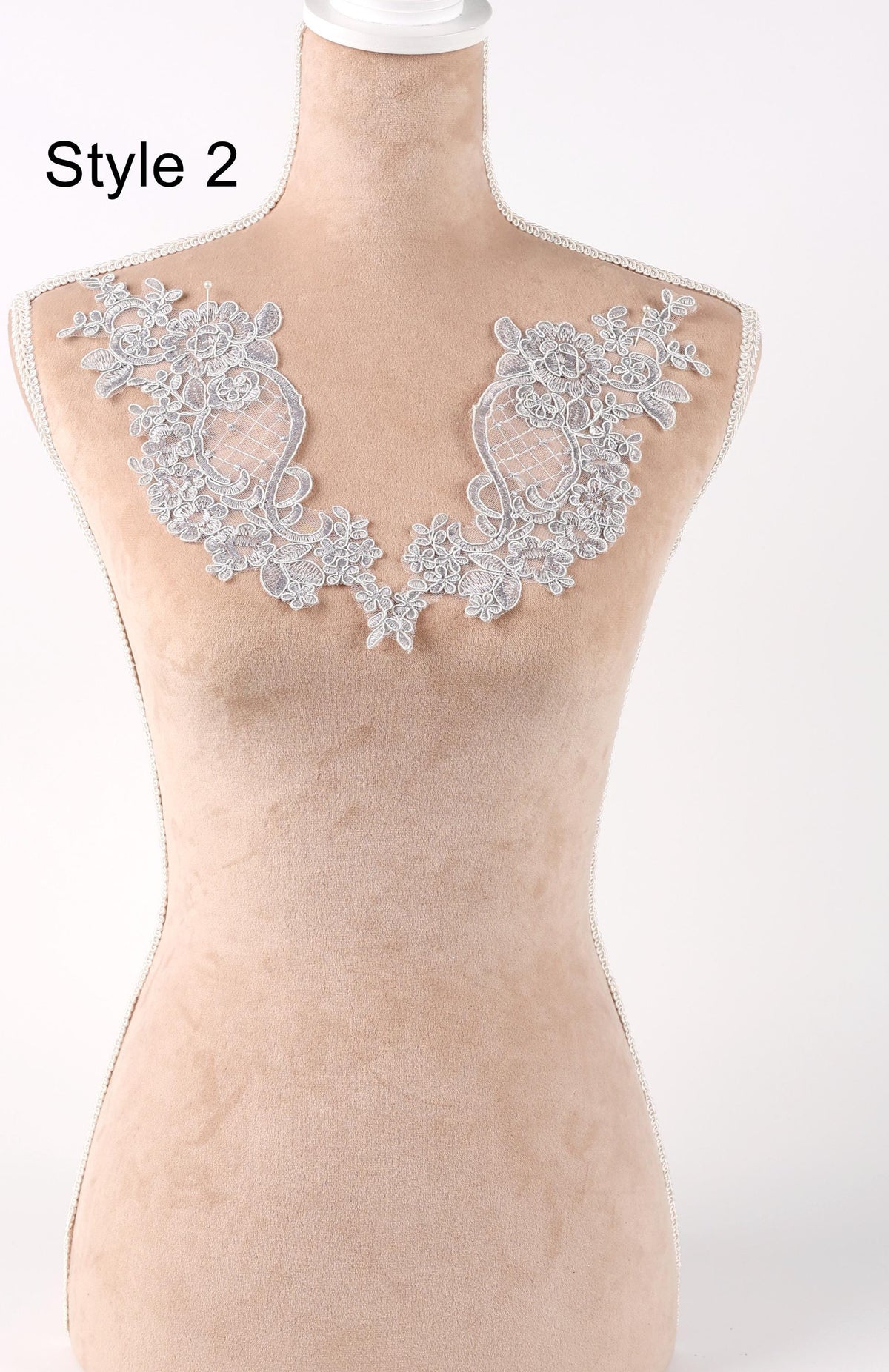 A mannequin wearing a beige dress with a decorative lace overlay on the chest area.