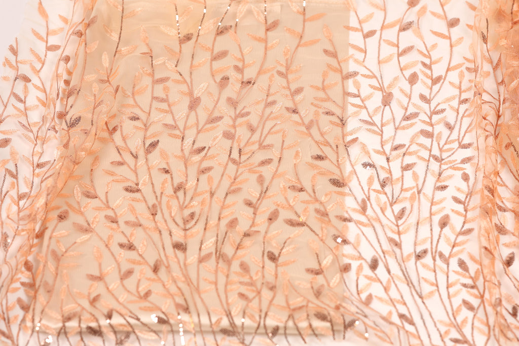 a close-up view of a fabric with a repeating pattern of leaves and branches in shades of peach and brown.