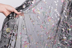 A hand is holding a piece of fabric with a floral pattern, which appears to be a black and white fabric with colorful floral designs.