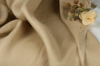 a close-up view of a beige fabric with a small bouquet of yellow flowers resting on it.