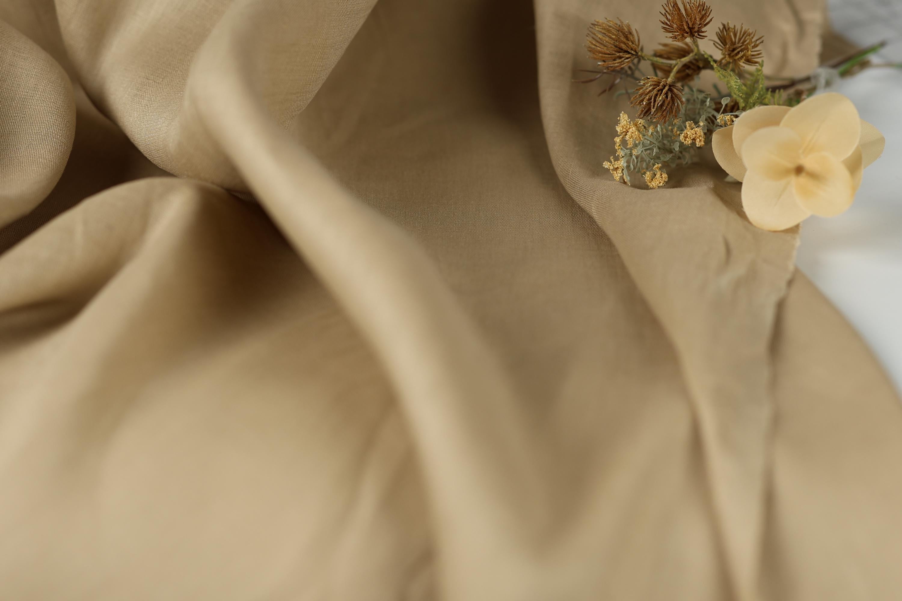 a close-up view of a beige fabric with a small bouquet of yellow flowers resting on it.
