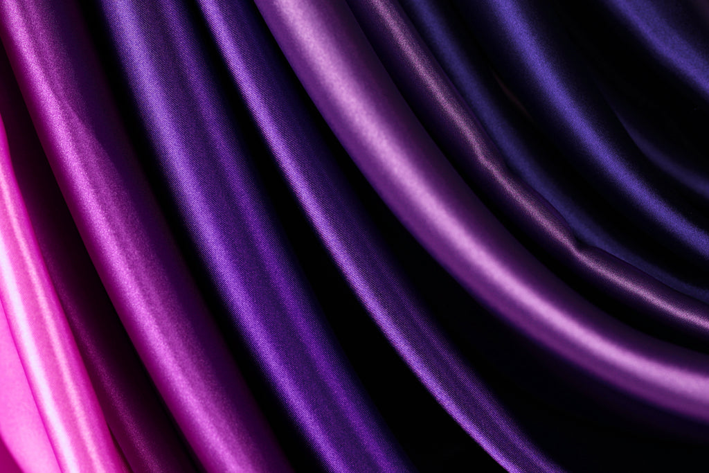 a close-up view of a fabric with a gradient of purple and pink hues, creating a visually striking and vibrant pattern.