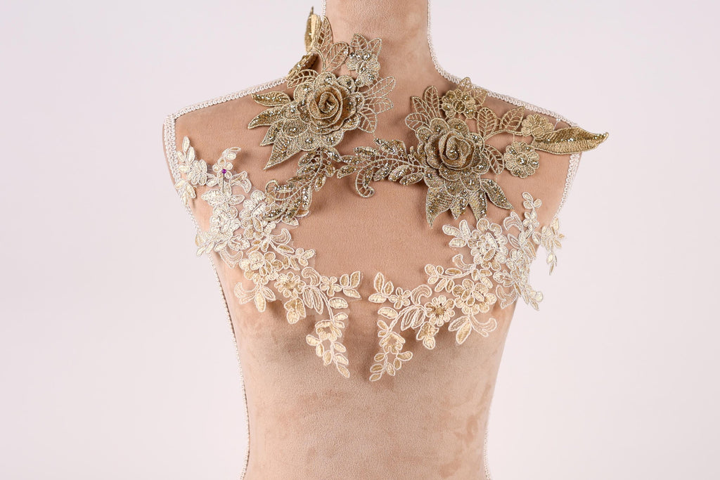 A mannequin wearing a gold and white floral dress with intricate lace details.