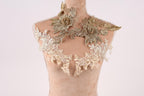 A mannequin wearing a gold and white floral dress with intricate lace details.